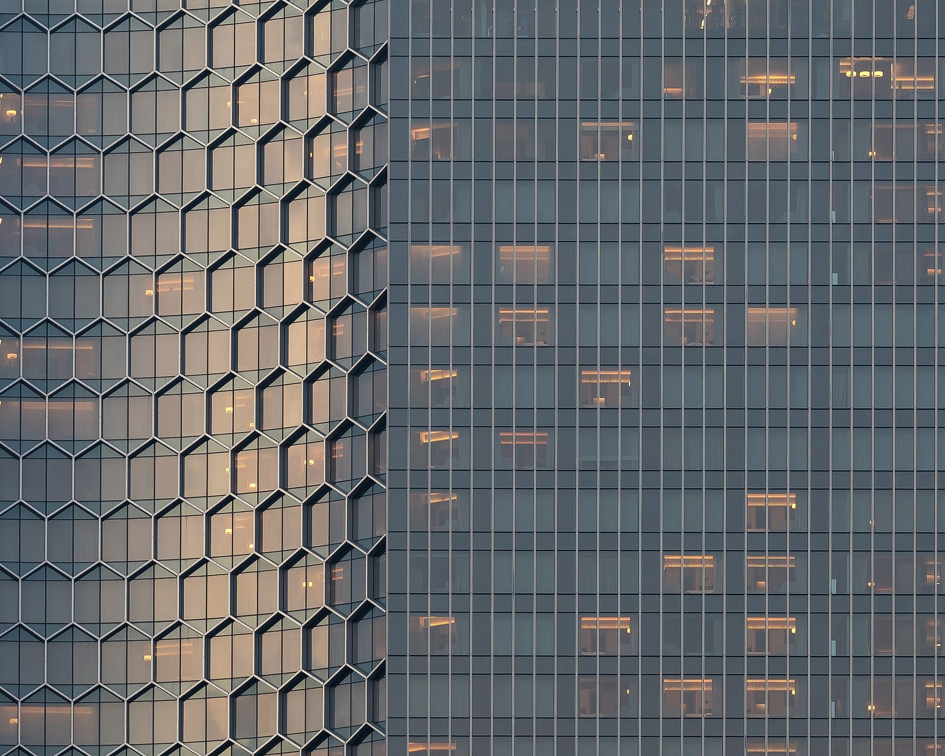 Sunlight and interior light mixing on a curved glass facade at dusk.