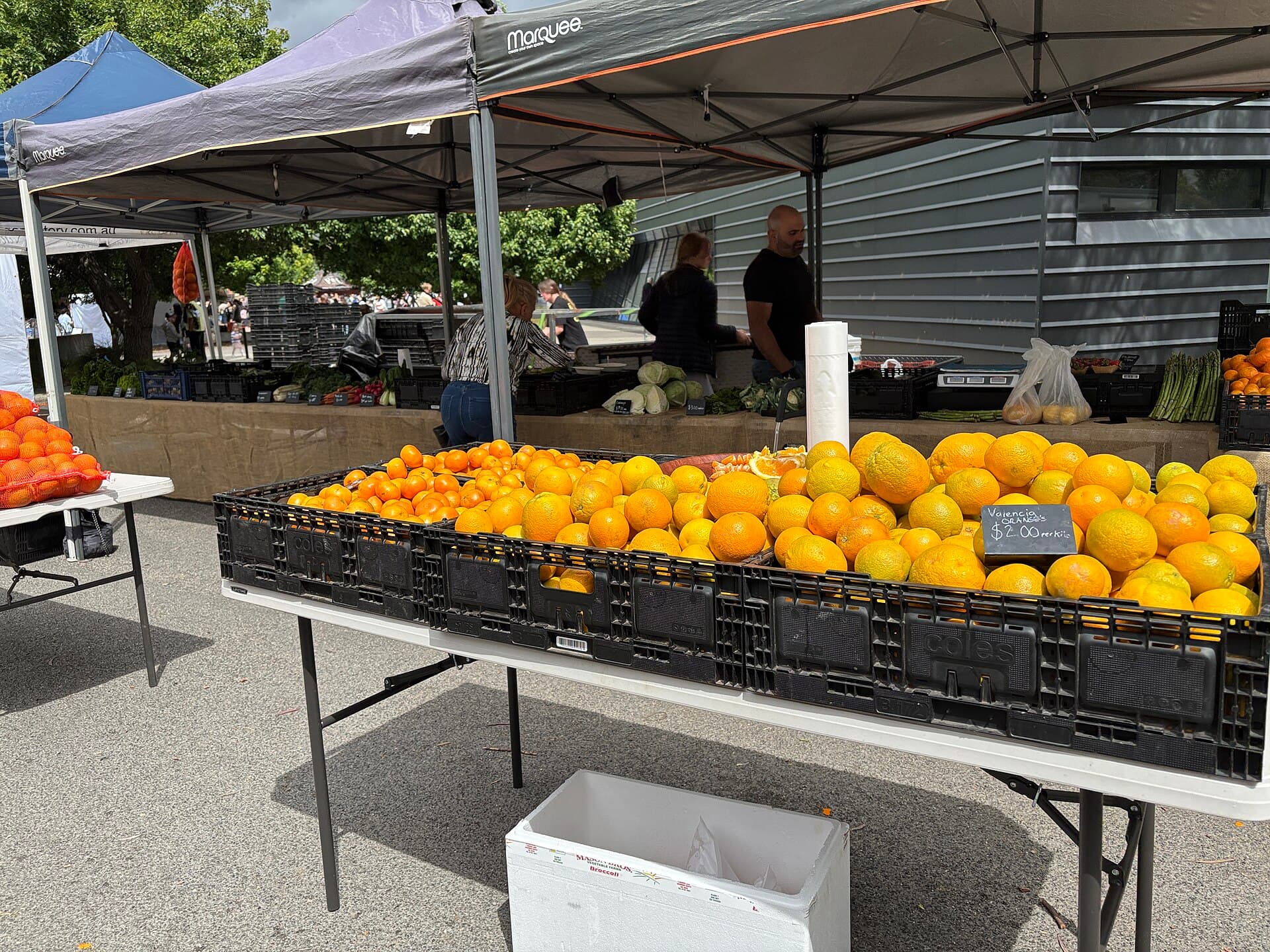 Colorful fruit and vegetables displayed at an outdoor farmers market stall.
