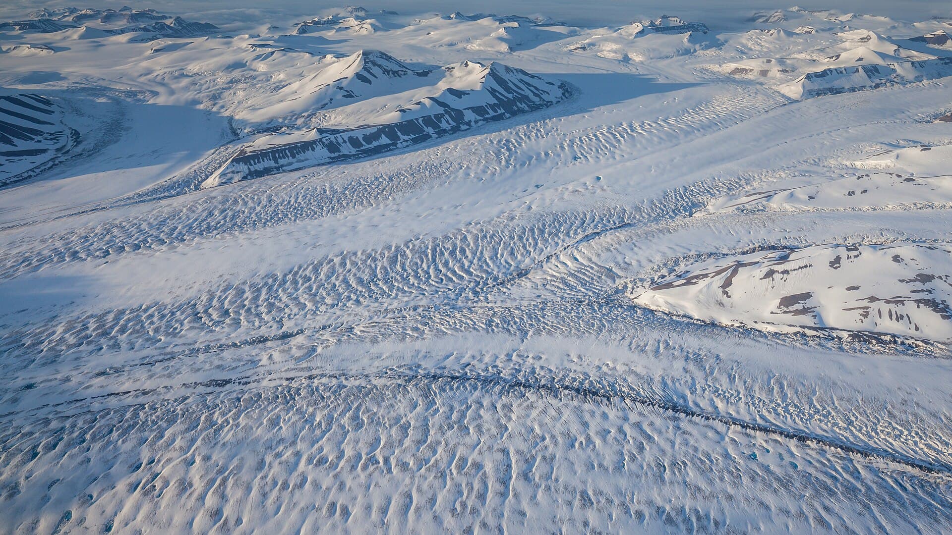 In the approach to Longyearbyen, Svalbard, the plane from Oslo crosses the Nathorst glacier on Torrell Land. During good weather conditions the numerous inflows to the central glacier can be observed. The image was taken close to midnight with a bright shining midnight sun.