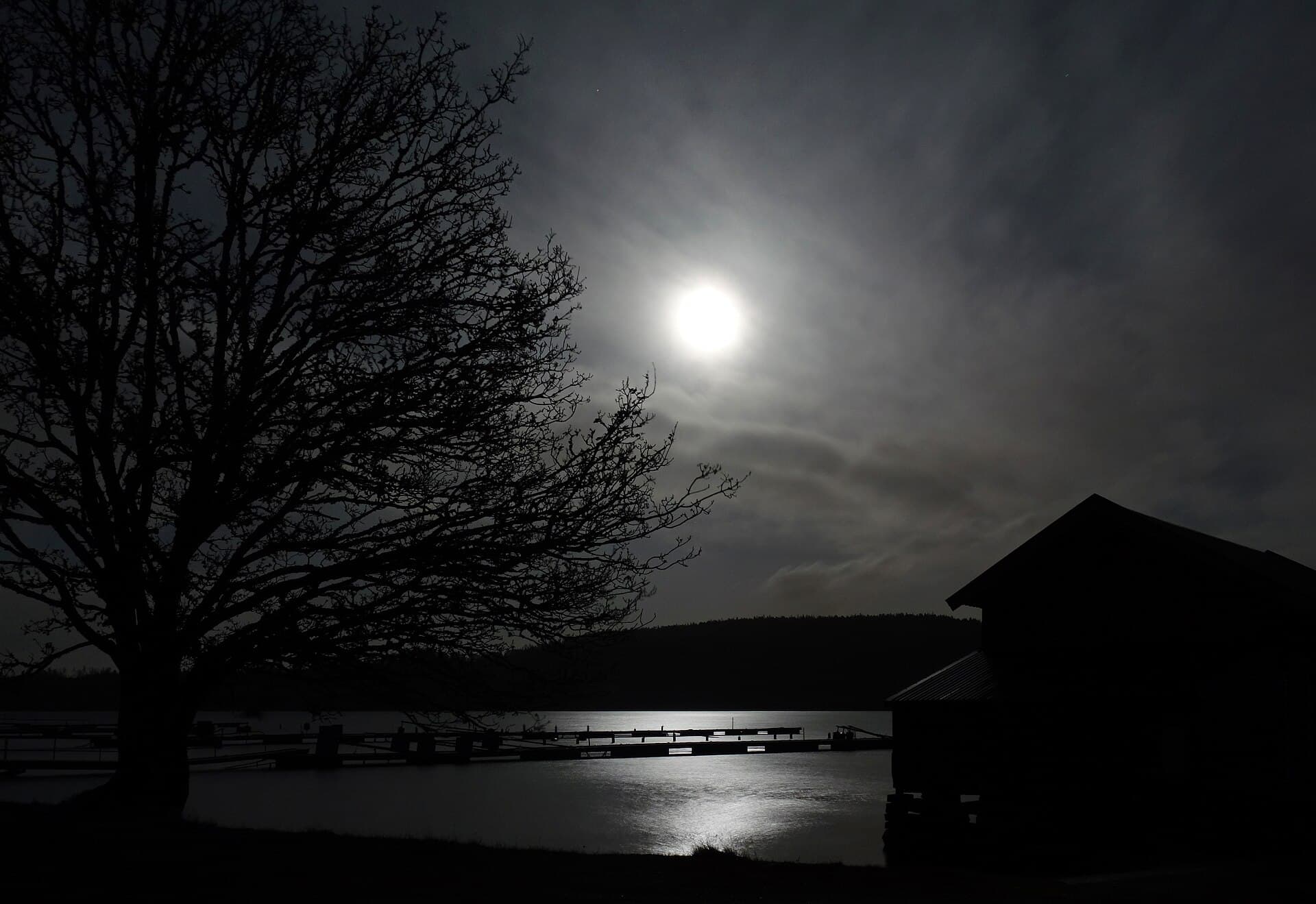 A full moon shining though the clouds over Holma Marina at Gullmarn fjord in Lysekil Municipality, Sweden.