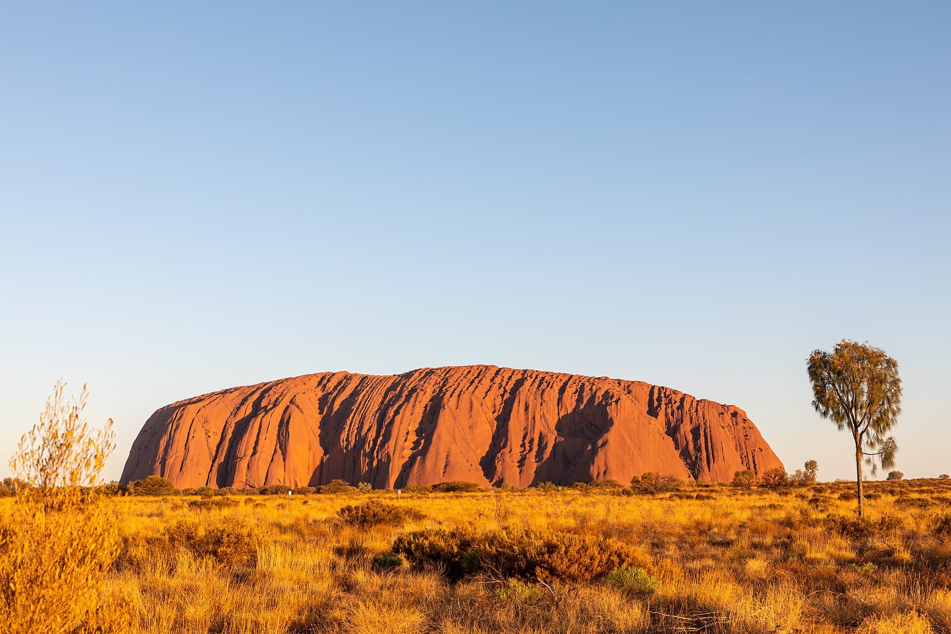 Uluru at sunset in the Australian outback, with red earth and wide open sky.