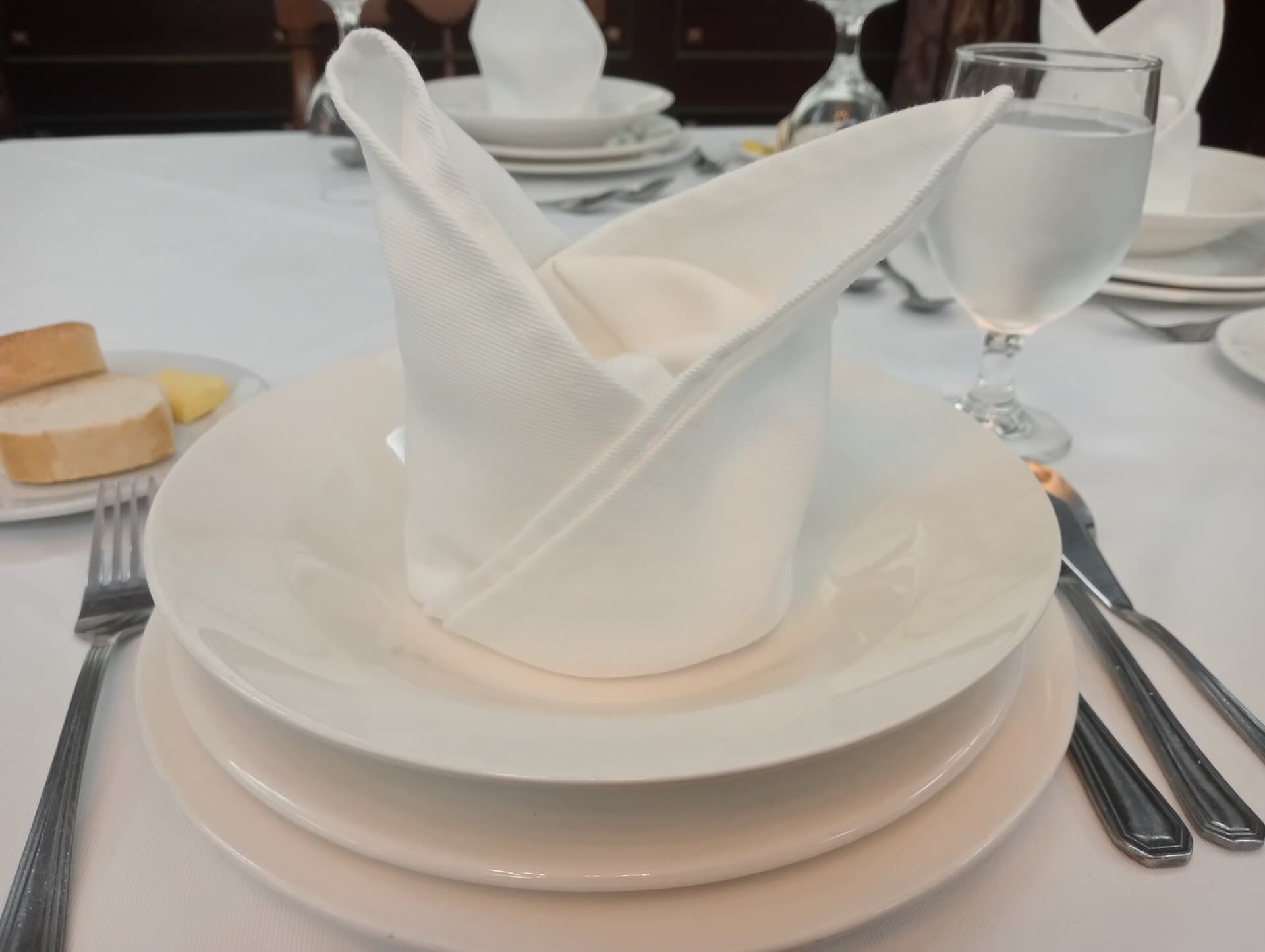 A set dining table with a folded napkin, waiting for a meal.